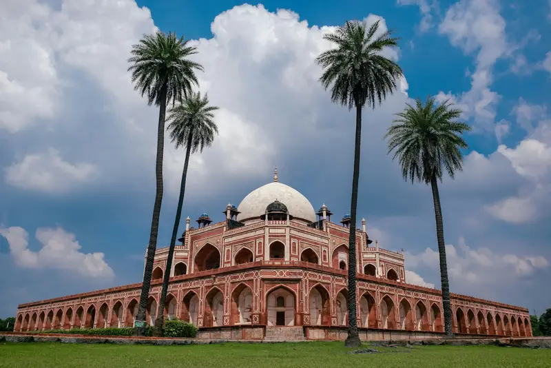 Humayun's Tomb framed by tall palm trees and clouds