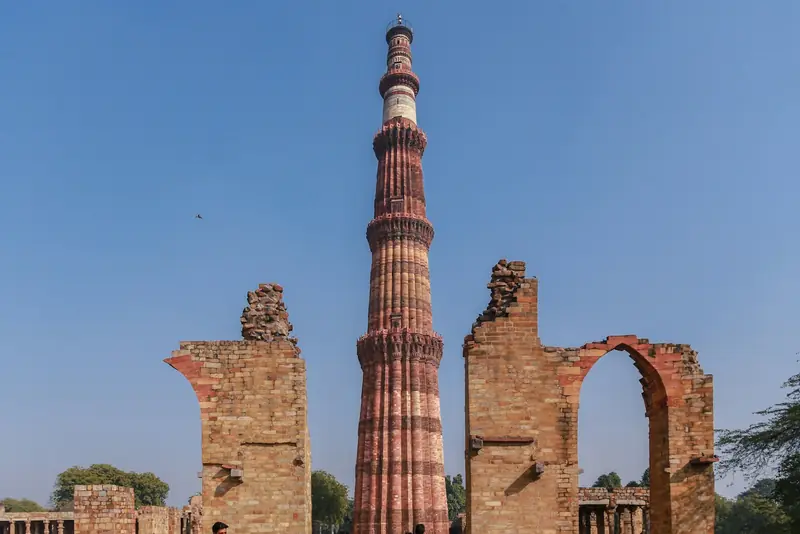 The Qutub Minar tower beside the ruined arches of the Qutb complex in Delhi