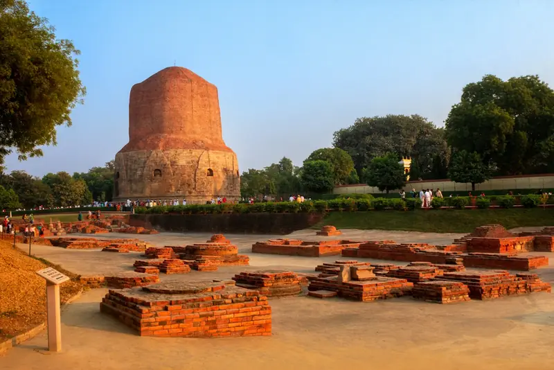 Ancient brick monastery ruins with the Dhamek Stupa behind, Sarnath