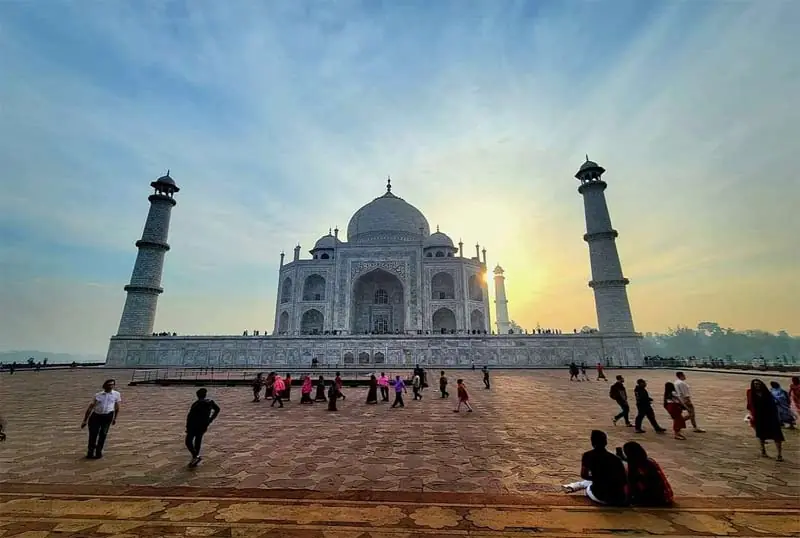 The Taj Mahal at sunrise with visitors on the main platform