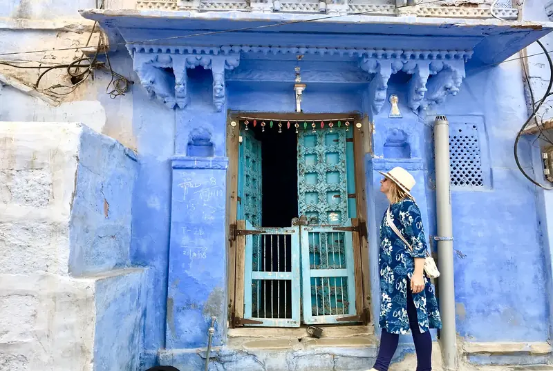 Traveller standing beside a blue-painted doorway in Jodhpur