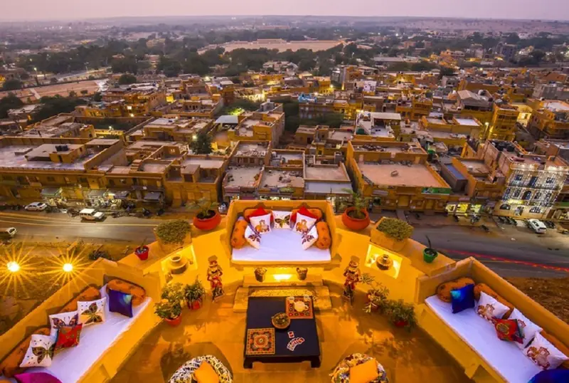 Rooftop seating lit at dusk overlooking a Rajasthan city