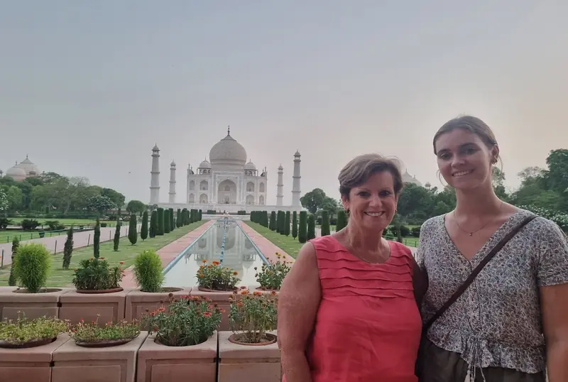 Two travellers smiling in front of the Taj Mahal